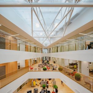 Architectural picture of the inside of the School of Business. Many people sitting on different coloured chairs.